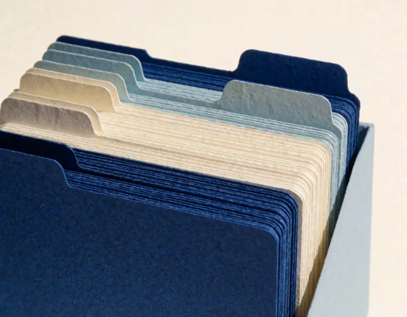 Ein offener Karteikasten aus blauem Papier, gefüllt mit aufrecht stehenden Karten und Registerreitern.