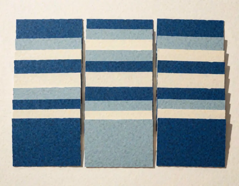 Papierkarten in gleichmäßigen Reihen auf einer Fläche ausgelegt, leicht überlappend, in Blau, Graublau und Creme.