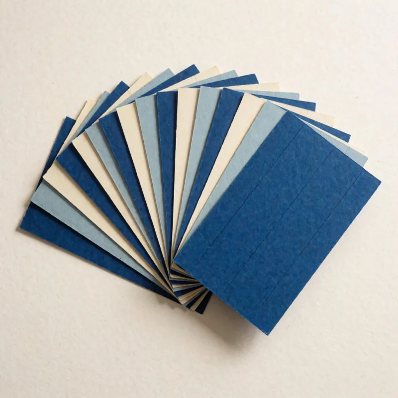Ein aufgefächerter Kartenstapel aus Papier in tiefem Blau, Graublau und Creme, in einem weiten Bogen ausgelegt.